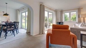 En moderne stue med en sofa, et spiseområde med stole og et stort vindue.