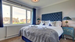 Et soveværelse med en stor seng, et vindue, en radiator og et natbord med lamper.