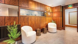 A reception area with wooden paneling, two white armchairs, a potted plant, and a fire exit sign. - The Kylestrome Deluxe - King or Twin (Ayr)