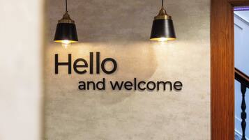 Un muro con il testo 'Hello and welcome' e due lampade a sospensione.