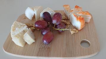 A wooden board with cheese, grapes, and bread.