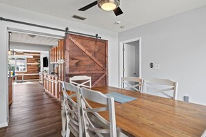 Eine moderne Küche mit Holzausstattung, ein Essbereich mit einem Holztisch und Stühlen sowie eine Schiebetür im Scheunenstil.