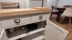 A kitchen with a wooden countertop, white cabinets, and a dining area with chairs. - Peaceful Oasis Private Basement Suite With Queen Bed & Full Kitchen (Shawinigan)