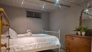 A bedroom with a bed, a dresser, a mirror, a window with blinds, and a ceiling with recessed lighting. - Peaceful Oasis Private Basement Suite With Queen Bed & Full Kitchen (Shawinigan)