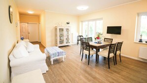 Une pièce comprenant une table à manger, des chaises, un canapé, un meuble et un téléviseur.
