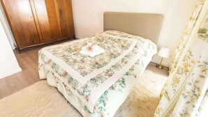 A bedroom with a bed, a wooden wardrobe, a fluffy rug, and floral curtains. - FeWo Nostalgie im Ferienidyll am Großen Wentowsee (Gransee)