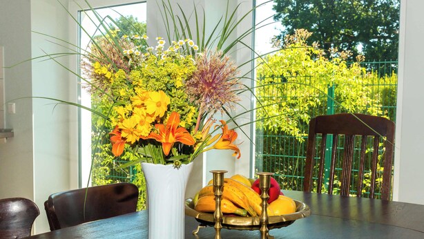 A dining table with a white vase of flowers, a fruit bowl, and a chair. - FeWo Nostalgie im Ferienidyll am Großen Wentowsee (Gransee)