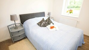 A bedroom with a bed, two bedside tables, a window with a view, and a radiator. - FeWo Klassisch – Ihrem Rückzugsort direkt am Großen Wentowsee (Gransee)