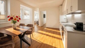 A modern kitchen with a wooden dining table, chairs, and a vase of flowers. - BERGNEST – Private Terrace & Garden (Voldöpp)