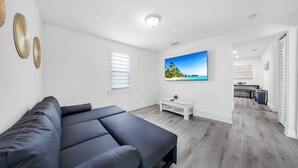 A modern room with a grey sofa, a flat-screen TV, and a white coffee table. - Miami Tree House Renovated Beach Jacuzzi (Miami)