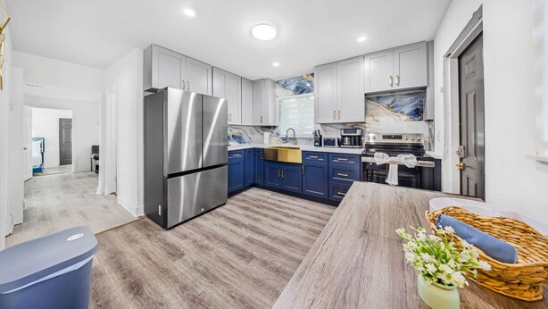 A modern kitchen with grey cabinets, a stainless steel refrigerator, and a wooden dining table. - Miami Tree House Renovated Beach Jacuzzi (Miami)