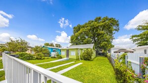A residential area with a green house, white fence, and a pathway leading to the house. - Miami Tree House Renovated Beach Jacuzzi (Miami)
