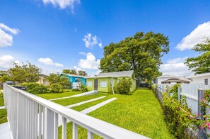 A residential area with a green house, white fence, and a pathway leading to the house. - Miami Tree House Renovated Beach Jacuzzi (Miami)