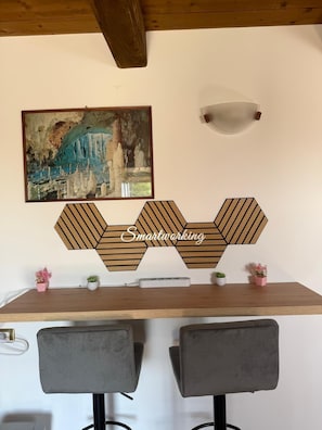 Ein Essbereich mit einem Holztisch, zwei grau gepolsterten Stühlen, einem Wandbild und einer geometrischen Wanddekoration.