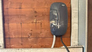 A wooden wall with a metal shelf, a black device, and a black cable. - Affittacamere Castelmanardo (Amandola)