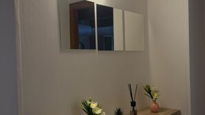 A hallway with a light fixture, a mirror, and a shelf with vases and a small plant. - Affittacamere Castelmanardo (Amandola)