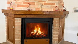 A fireplace with a brick mantel, a stone base, and a wooden door. - Affittacamere Castelmanardo (Amandola)