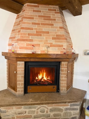 Una chimenea con repisa de ladrillo, base de piedra y puerta de madera.