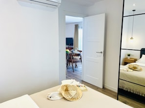 A hotel room with a bed, bedside table, and a view into the dining area. - Apartamento Azure Burriana by At Home Costa del So (Nerja)