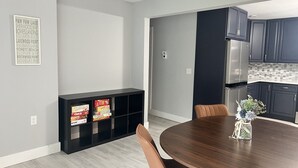 Una cucina moderna con pensili scuri, un frigorifero in acciaio inossidabile e un tavolo da pranzo in legno con sedie.