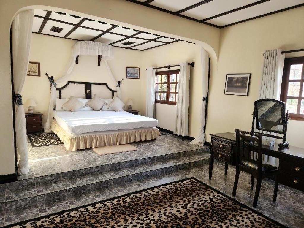 Une chambre à coucher avec un lit, un bureau, une chaise, une fenêtre et une porte.