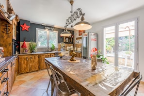A kitchen with wooden cabinets, a large island, and a refrigerator. - Charming Provence Villa with Pool, Wi-Fi, and Air Conditioning (Rochegude)