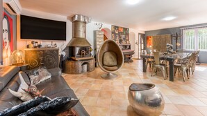 Un salon moderne avec une cheminée, un canapé, un coin repas avec des chaises et un téléviseur fixé au mur.