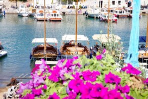 Ein Yachthafen mit mehreren angestaubten Booten, freier Blick auf das Wasser und im Vordergrund bunte Blumen.