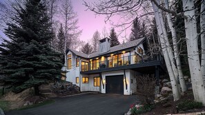 Ein zweistöckiges Haus mit Garage, umgeben von Bäumen und einer Auffahrt.