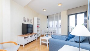 Una sala de estar moderna con televisor, sofá y comedor.