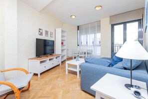 Ein modernes Wohnzimmer mit Fernseher, einer Couch und einem Essbereich.