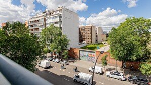 Un edificio de varios pisos con balcones, un estacionamiento y una calle con vehículos.
