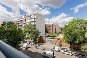 Ein mehrstöckiges Gebäude mit Balkonen, einem Parkplatz und einer Straße mit Fahrzeugen.