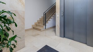 Una escalera con barandilla metálica que conduce a un ascensor gris.
