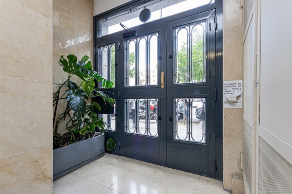 Eine schwarze Tür mit Glasscheiben, ein Blumentopf und ein Schild an der Wand.
