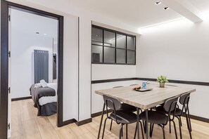 Ein modernes Zimmer mit einem Holzespeisetisch, vier Stühlen, einer Topfpflanze und einem großen Fenster.