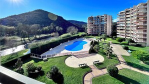 A residential area with a swimming pool, a river, and a mountain in the background. - Apartment with Terrace & Pool, Mandelieu (Mandelieu-la-Napoule)