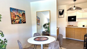 A modern kitchen with a microwave, a dining area with a round table and chairs, and a large mirror. - Apartment with Terrace & Pool, Mandelieu (Mandelieu-la-Napoule)