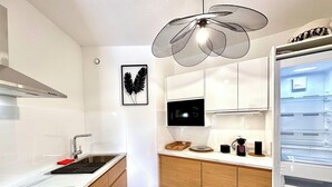 A modern kitchen with a built-in microwave, a sink, and a unique ceiling fan. - Apartment with Terrace & Pool, Mandelieu (Mandelieu-la-Napoule)