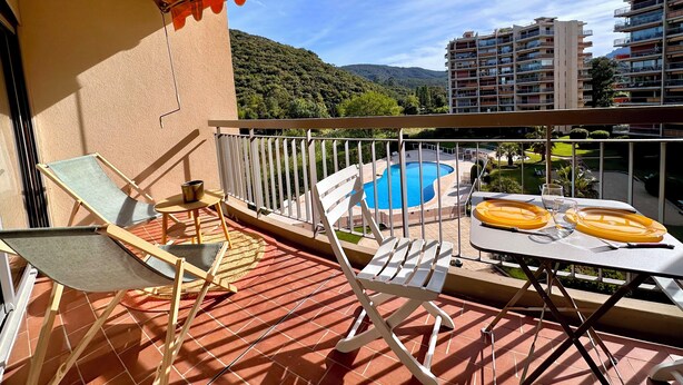 A balcony with a pool, chairs, and a table set for dining. - Apartment with Terrace & Pool, Mandelieu (Mandelieu-la-Napoule)
