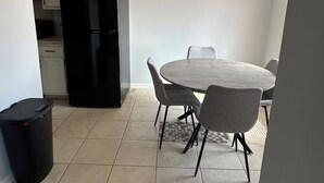 A kitchen with white cabinets, a black refrigerator, and a dining area with a round table and four chairs.