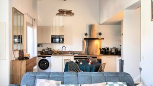 Un espace de vie compact comprenant un canapé, un lave-linge, un four à micro-ondes et un coin repas.