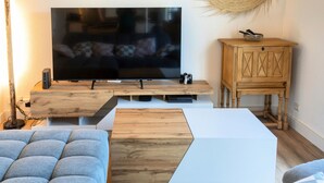 Un salon moderne avec un téléviseur à écran plat, un meuble en bois et un canapé.