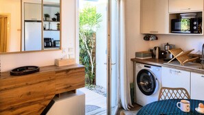 Une cuisine compacte équipée d’un lave-linge, d’un four à micro-ondes et d’une machine à café.