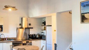 Une cuisine moderne avec un coin repas, des appareils en acier inoxydable et un luminaire suspendu.