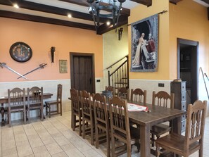 A dining area with a wooden table and chairs, a clock, and a painting on the wall.
