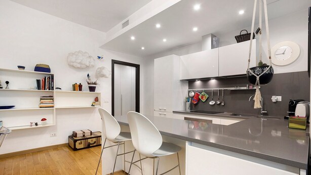 A modern kitchen with white cabinetry, a grey countertop, and a hanging macrame pot. - Comfortable Apartment Steps from the Red Metro Line (Milano)