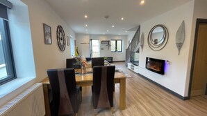 A dining area with a wooden table, chairs, and a modern fireplace. - Chapel Row 6, Wirksworth Peak District (with pac man machine ) (Wirksworth)