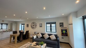A modern living room with a sofa, coffee table, and a dining area with chairs and a table. - Chapel Row 6, Wirksworth Peak District (with pac man machine ) (Wirksworth)