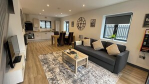 A modern living room with a sofa, coffee table, and a dining area with chairs and a table. - Chapel Row 6, Wirksworth Peak District (with pac man machine ) (Wirksworth)